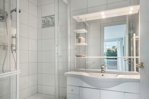 une salle de bain blanche avec un lavabo et un miroir dans l'établissement Appartement tout confort pour 4 à 300m de la plage, à La Baule