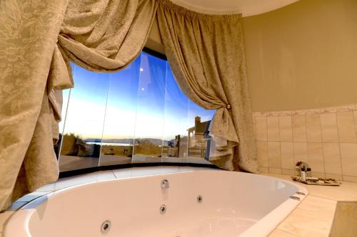 a bath tub in a bathroom with a window at Château La Mer Exclusive Guesthouse & Spa in Hartbeespoort