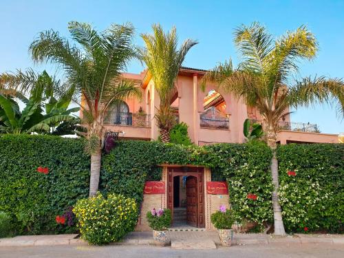 une maison rose avec des palmiers et des plantes dans l'établissement Riad Mazal, à Marrakech