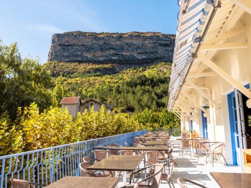 a balcony with tables and chairs with a mountain in the background at Village Club Les Lavandes - Neaclub in Rémuzat