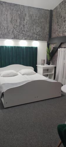 a bedroom with a large white bed with a green headboard at Karczma Rycerska Lebork in Lębork