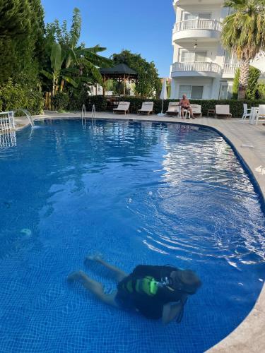 a woman laying in the water in a swimming pool at BELKA GOLF RESİDENCE Luxury Apt Poolside Belek in Belek