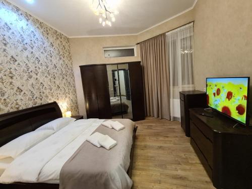 a bedroom with a bed and a flat screen tv at Nino's Cosy Apartment in Kutaisi