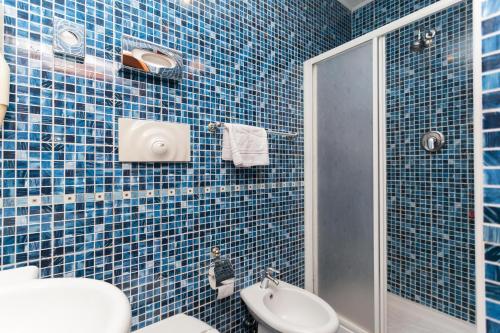 e bagno piastrellato blu con servizi igienici e doccia. di New Apartment Marghera a Milano