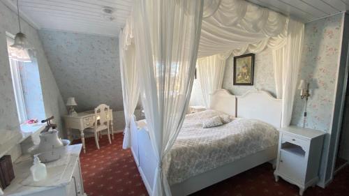 a bedroom with a white canopy bed with curtains at Svostrup Kro in Silkeborg