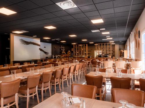 una sala da pranzo con tavoli, sedie e schermo di Village Club Les Lavandes - Neaclub a Rémuzat