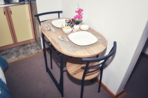 uma mesa de madeira com duas cadeiras e um prato sobre ela em Apartman Ippon em Police