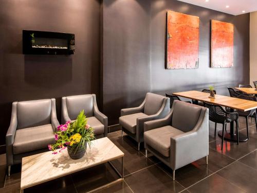 una sala d'attesa con sedie, tavoli e TV di ibis Sydney World Square a Sydney