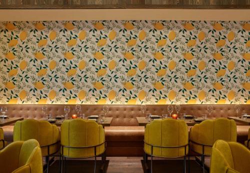 a dining room with tables and yellow chairs and a wall at Mar Monte Hotel, in The Unbound Collection by Hyatt in Santa Barbara