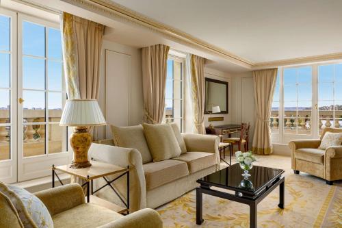 a living room with a couch and chairs and windows at Shangri-La Paris in Paris
