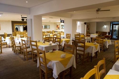 a restaurant with tables and chairs with yellow table cloth at Royal Seabank Hotel in Blackpool