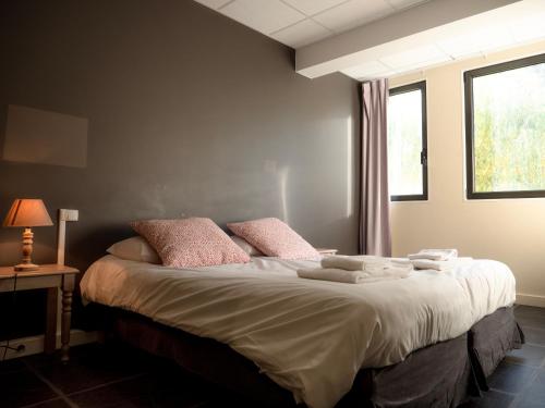 a bedroom with a bed with pink pillows and a window at Village Club Les Lavandes - Neaclub in Rémuzat