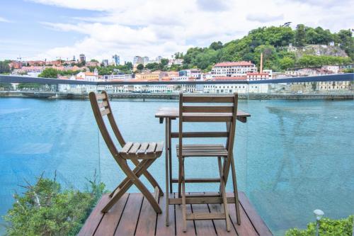 einen Tisch und einen Stuhl auf einer Terrasse mit Wasser in der Unterkunft Douro triplex - Destilaria Residence by Porto City Hosts in Vila Nova de Gaia