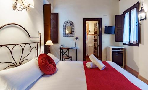 a bedroom with a large white bed with red pillows at Casa del Capitel Nazarí in Granada