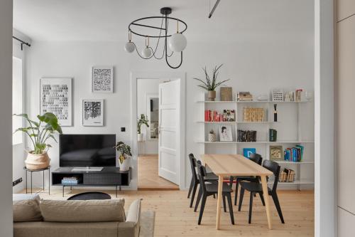 - un salon avec une table, des chaises et une télévision dans l'établissement Designer Apartment in Vinohrady by Prague Days, à Prague