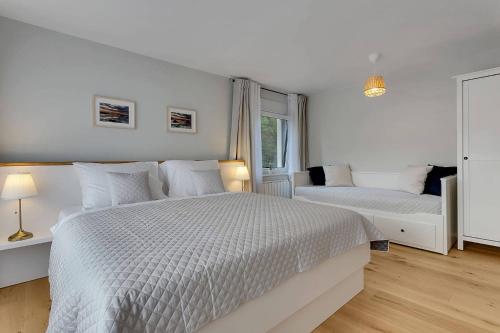 a white bedroom with two beds and a window at Angel Boutique Home - Entire premium house in Laško
