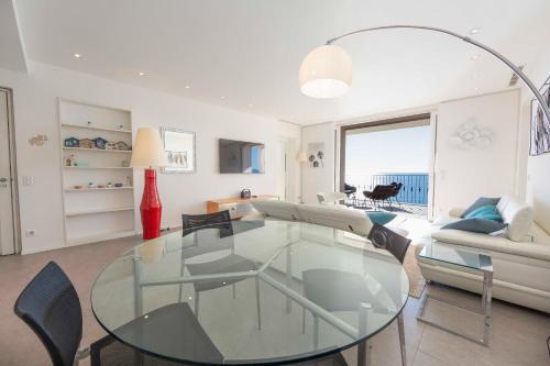 un salon avec une table en verre et des chaises dans l'établissement Appartement 3 chambres 125 m2 avec vue exceptionnelle face à la mer, à Cannes