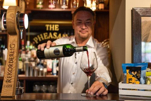 a man pouring wine into a wine glass at The Pheasant Inn - The Inn Collection Group in Bassenthwaite