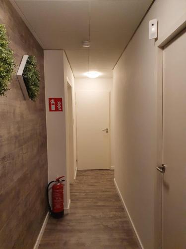 a hallway with a white door and a fire hydrant at De Gorzen in Oud-Turnhout