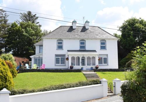 a white house with a green yard at Fitzgerald's Farmhouse Accommodation in Abbeyfeale