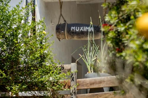 una señal que dice kushka colgando del lado de una casa con plantas en Muxima - Aljezur en Aljezur