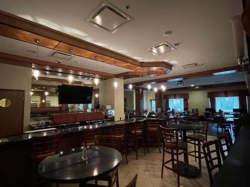 a restaurant with tables and chairs and a bar at Holiday Inn Battle Creek by IHG in Battle Creek