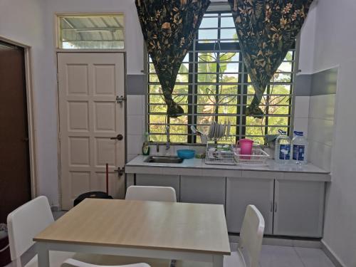 cocina con mesa, sillas y ventana en Homestay Pasir Tumboh Kota Bharu en Kota Bharu