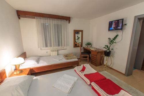 a bedroom with two beds and a desk with a window at Vila Castello in Bar, Susanj