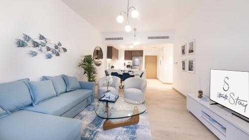 uma sala de estar com um sofá azul e uma mesa em Ultimate Stay - 4 Beds - La Mer - Sunset Marina View no Dubai