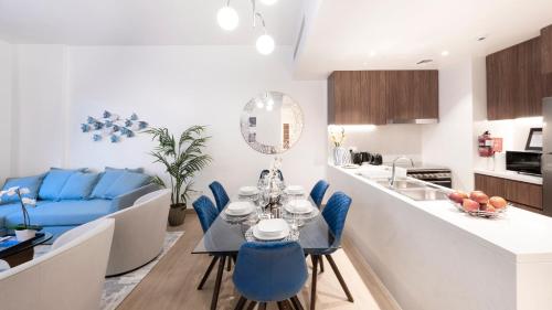 uma cozinha e sala de estar com uma mesa e cadeiras azuis em Ultimate Stay - 4 Beds - La Mer - Sunset Marina View no Dubai