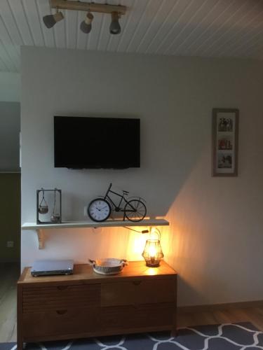 a living room with a tv on a white wall with a clock at 't Greefsch Geluck in Kalmthout