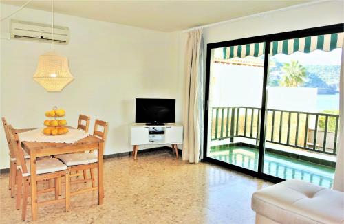 a living room with a table and a television and a balcony at Port de Sóller Promenade Apartment. in Port de Soller