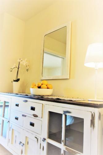 a bowl of oranges on a white dresser with a mirror at Port de Sóller Promenade Apartment. in Port de Soller
