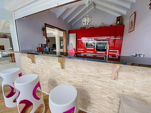 a kitchen with a counter with white stools at Villa Marie, swimming pool, beach, pontoon and jacuzzi, all private in Baie Nettle