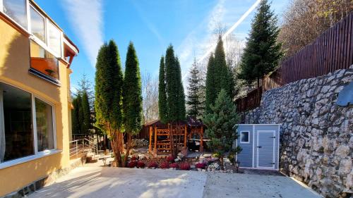 einen Garten mit Bäumen, einer Steinmauer und einem Gebäude in der Unterkunft Marble Villa: Luxury estate - central but intimate in Sinaia