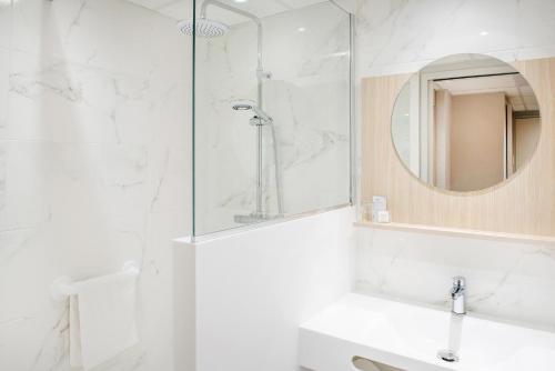 a bathroom with a shower and a sink and a mirror at Hôtel Saint Sauveur in Lourdes