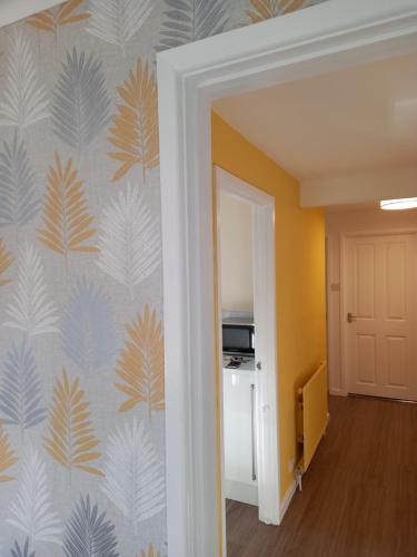 a hallway with a wall mural of leaves at Moore Apartment in Bourton on the Water
