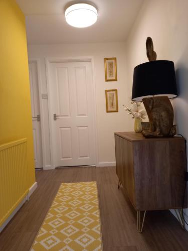 a living room with a lamp and a cat statue on a dresser at Moore Apartment in Bourton on the Water