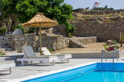 a chair and umbrella next to a swimming pool at Amperian Mykonos Suites & Villas in Mýkonos City