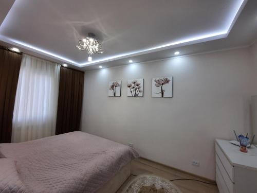 een slaapkamer met een bed en drie foto's aan de muur bij NEST FOR REST in Tasjkent