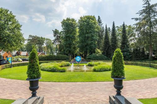 a garden with a fountain and trees in a park at Landgoed de Scheleberg in Lunteren