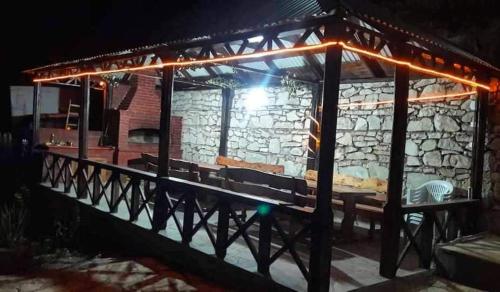 a stone building with a table and benches at night at Green garden Կանաչ այգի in Ijevan