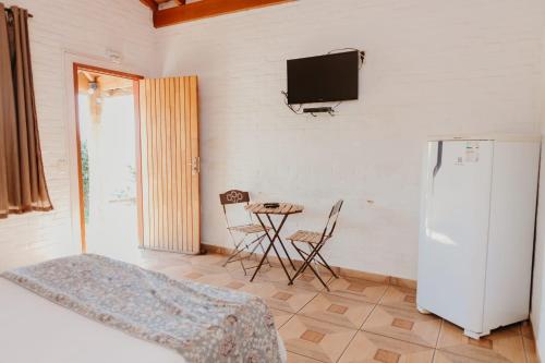 a room with a refrigerator and a table and a tv at Pousada Cafune in Socorro