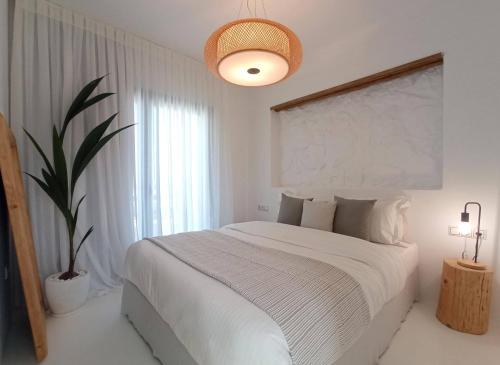 a bedroom with a white bed and a potted plant at The Nine Graces - Kastraki Villas with Private Swimming Pool in Kastraki Naxou
