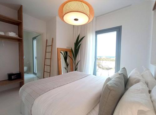 a bedroom with a white bed and a large window at The Nine Graces - Kastraki Villas with Private Swimming Pool in Kastraki Naxou