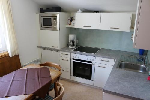a kitchen with white cabinets and a sink and a table at Haus Alpina in Sonnenalpe Nassfeld