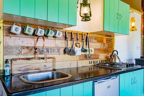 a kitchen with green cabinets and a sink at AfriCamps at Oakhurst in Wilderness
