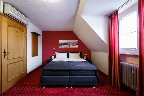 a bedroom with a bed and a red wall at Hotel Rüdesheimer Hof in Rüdesheim am Rhein