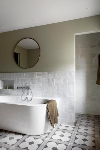 a white tub in a bathroom with a mirror at Baumanière - Les Baux de Provence in Les Baux-de-Provence