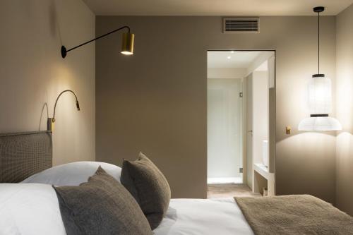 a bedroom with a bed with pillows and a mirror at Baumanière - Les Baux de Provence in Les Baux-de-Provence